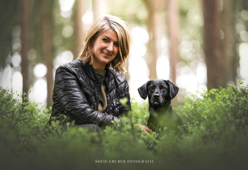 Kundin Sabine Schulz mit ihrem Hund, sitzend im Gras