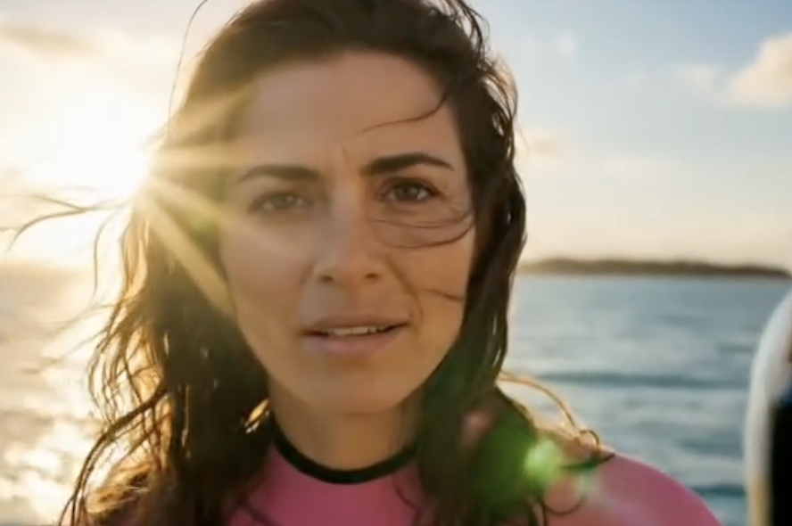 Frau mit langen braunen haaren schaut in die kamera, hintgrund meer AI Projekt